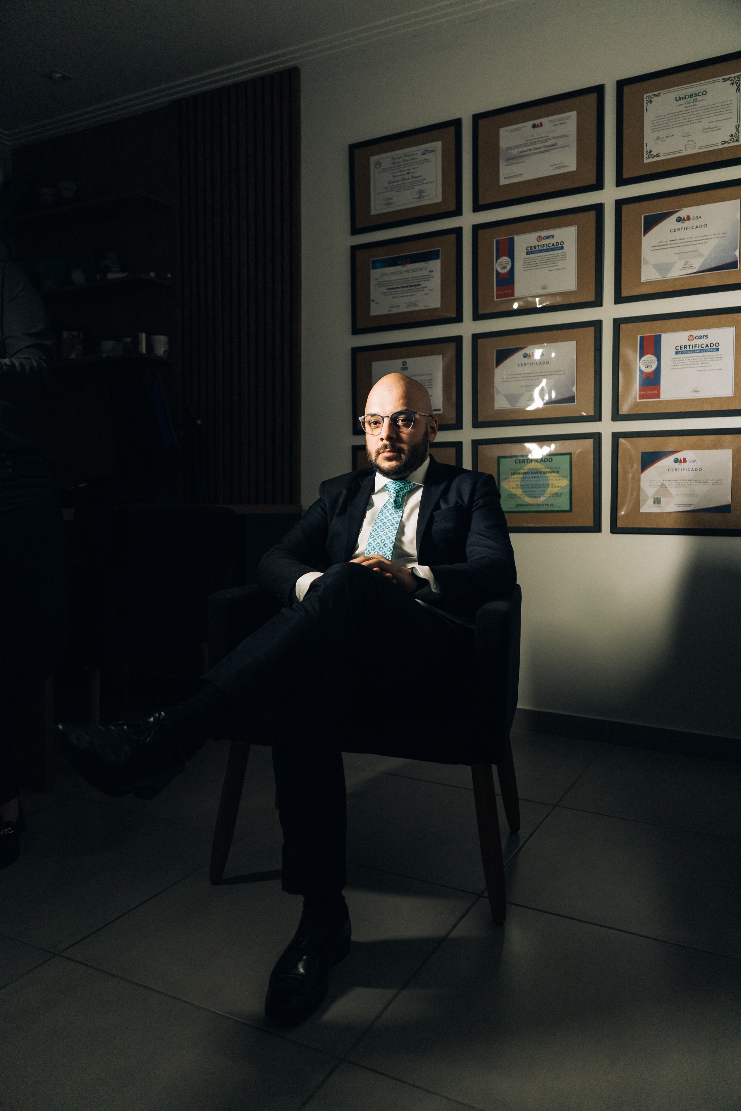 Leonardo Sampaio, professor universitário de Direito, ao lado de seus certificados e diplomas